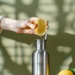 Eco-friendly lemon squeezing into a stainless steel bottle promotes zero waste lifestyle.