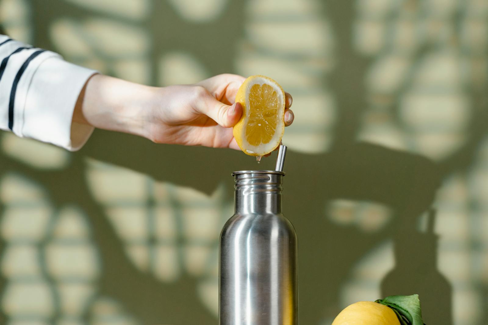 Eco-friendly lemon squeezing into a stainless steel bottle promotes zero waste lifestyle.