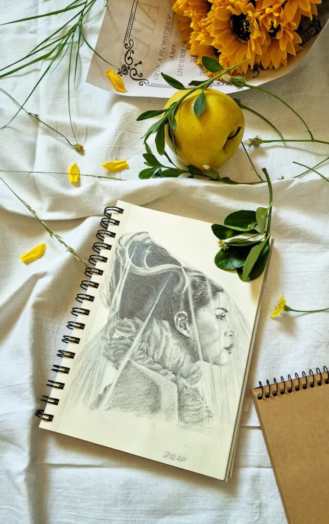 A notepad with a drawing of a woman on it next to a bowl of