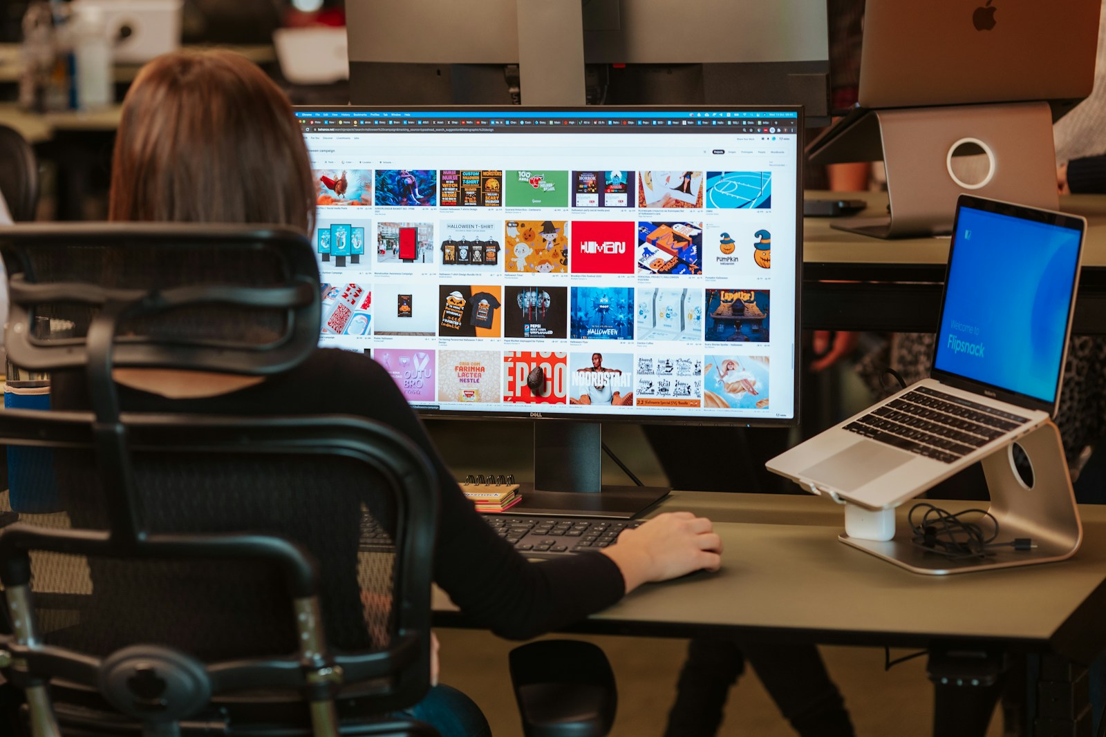 a woman sitting in front of a computer monitor