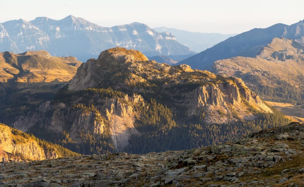 Sunlight illuminates rugged mountains and valleys under a clear sky.