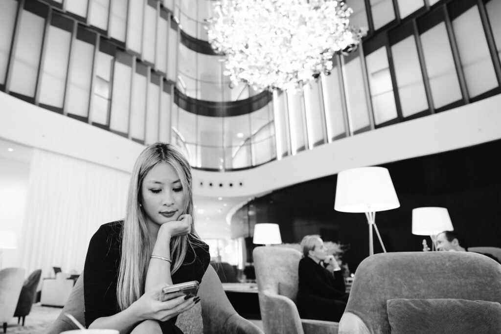 Hotel lobby with a traveller checking a phone, representing how AI search & editorial coverage now shapes hotel booking decisions